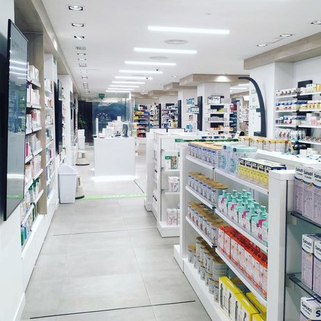 Interior de una Farmacia Amiga: el pasillo central, las estanterías a ambos lados y el mostrador al fondo.